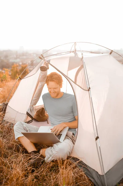 A ginger man sitting in the tent and watching something online — Stock Photo, Image