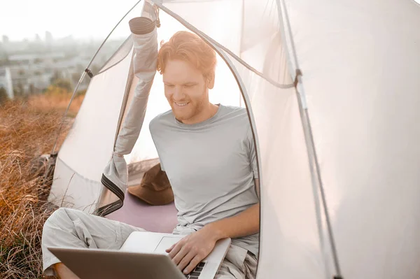 A ginger man sitting in the tent and watching something online — Stock Photo, Image