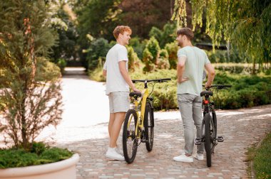 Bisikletli iki arkadaş dışarıda sohbet ediyorlar.