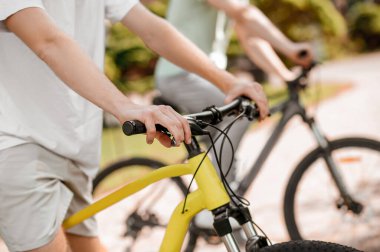 İki beyaz sporcu parkta birlikte bisiklete biniyor.