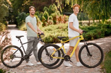 Bisikletleri ileri bakan iki çekici genç bisikletçi.