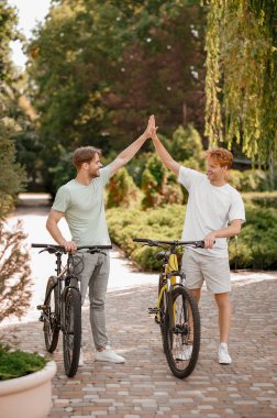 Dışarıda birbirini selamlayan iki bisikletçi.