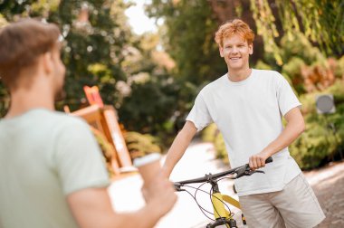 Memnun genç bisikletçi arkadaşıyla sohbet ediyor.