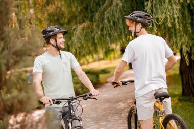 Kasklı bisikletçiler parkta birbirleriyle konuşuyorlardı.