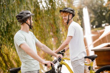 Dışarıda duran koruyucu başlıklı iki bisikletçi.