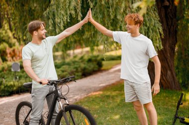 Bisikletçi kızıl saçlı arkadaşına beşlik çakıyor.