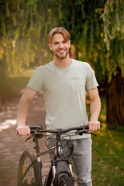 Gioioso ciclista maschio in piedi in un parco — Foto Stock