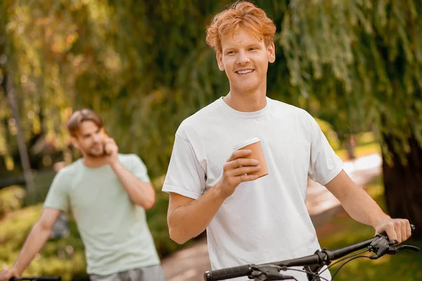 コーヒーブレイク中の笑顔の自転車乗りと彼の仲間 — ストック写真