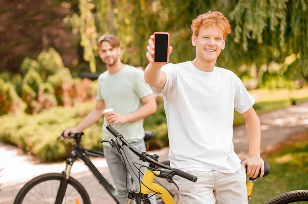 Dos jóvenes ciclistas de pie en un parque — Foto de Stock