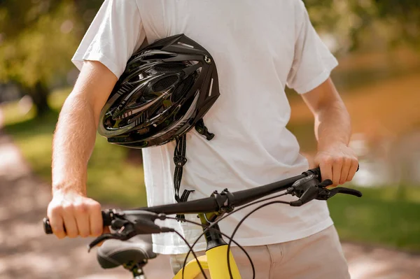 Manos masculinas sosteniendo casco y bicicleta — Foto de Stock
