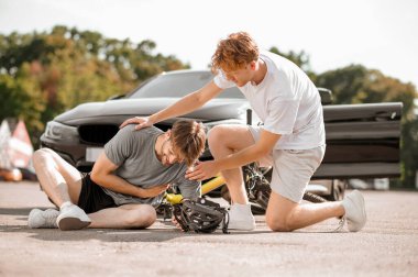 Kızıl adam yaralı bir bisikletçiyi destekliyor.