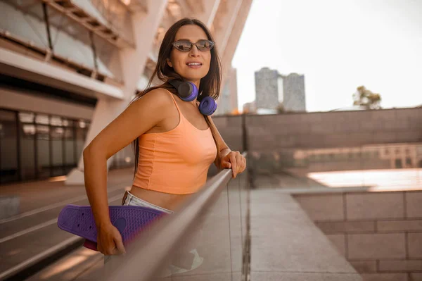 Şehir arka planında turuncu bluzlu şirin bir kız resmi. — Stok fotoğraf