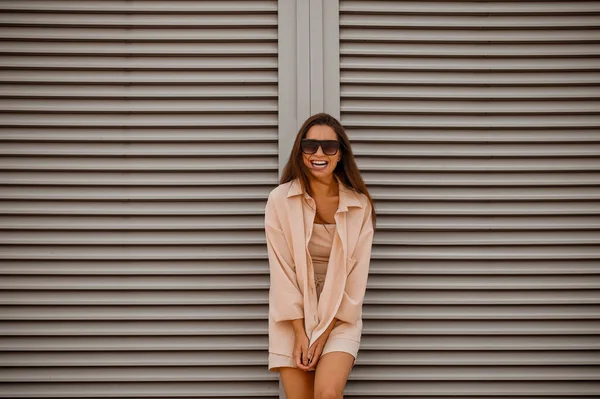 Eine junge hübsche Frau in beiger Kleidung und Sonnenbrille — Stockfoto