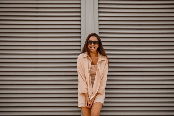 Una joven guapa vestida de color beige y con gafas de sol —  Fotos de Stock