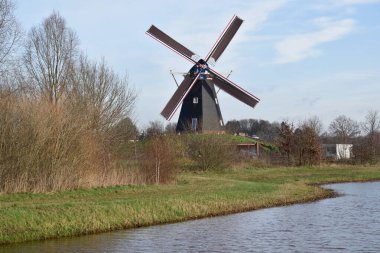 Güzel Hollanda yel değirmeni mavi kış gökyüzünün altında rahatlatıcı bir kanala bakıyor.