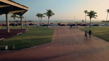 Hava aracı Plaza Gobernadores Parkı 'ndan denize doğru gidiyor. Çocuklar Ciudad Madero Tamaulipas' da Sunset 'te koşuyor ve Palm Trees seyrediyor.