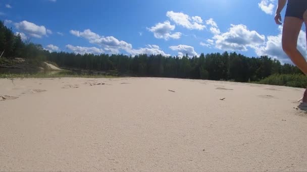 日当たりの良い川のビーチに沿って男 足のビュー が散歩 — ストック動画