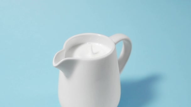 Una gota de leche gotea en una jarra de leche llena — Vídeos de Stock