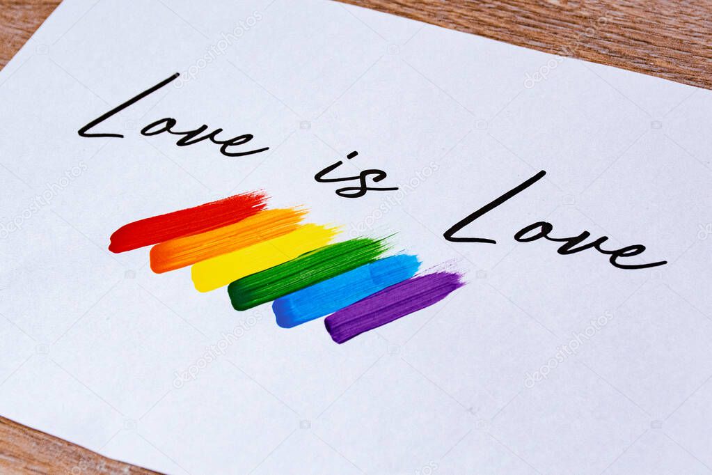Love is Love slogan and flag with the LGTBI colors, red, orange, yellow, green, blue and purple made with acrylic paint and brush. Pride day