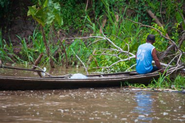 Amazon nehrinde geleneksel ahşap bir teknede yerli bir adam.