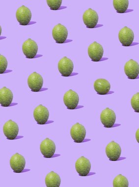 Pastel menekşe arkaplanına karşı yeşil limondan yapılmış yaratıcı meyve deseni. Minimum konsept. Düz yatıyordu.