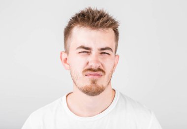 Dağınık saçlı, kasvetli gülüşlü, gri arka planda duran tatminsiz, uykulu adam.