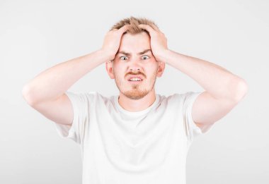 Utangaç, modaya uyan, zorluklardan korkan genç bir adam beyaz arka plana karşı duruyor..