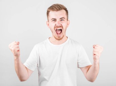 Gri arka plandaki zaferi kutlayan genç adam.