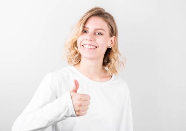 Gülümseyen güzel bir genç kadın beyaz arka planda baş parmak gösteriyor..