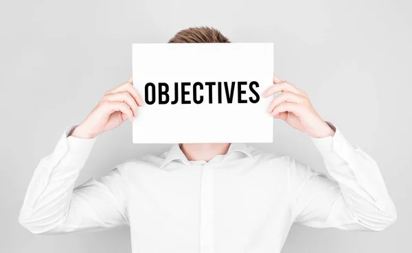 Hombre Cubre Cara Con Libro Blanco Con Texto Objetivos — Foto de Stock