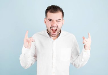 Çılgın bir ifadeyle bağıran adam elleri havada rock sembolü yapıyor. Ağır konsept.