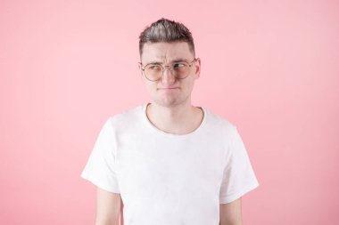 Şüpheci bakışlı genç çekici bir adam, bazı şüpheleri ve belirsizlikleri var, merakla başka yere bakıyor, beyaz arka planda mesaj için yer var.