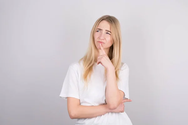 stock image Portrait of young woman thinking with her finger to her head and looks to the side