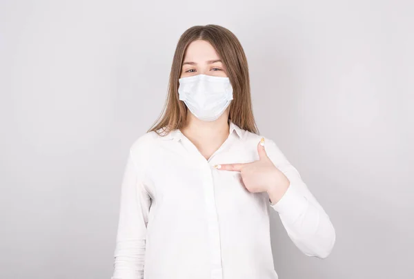 若い女性は自分で指を指差す コロナウイルス感染や風邪の予防のためのマスクを着用することの重要性を示しています — ストック写真