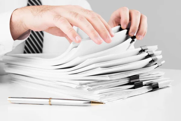 Businessman hands working in stacks of paper files for searching information, business and financial concept