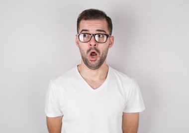 Gri arka plana bakan şok olmuş genç bir adamın portresi..