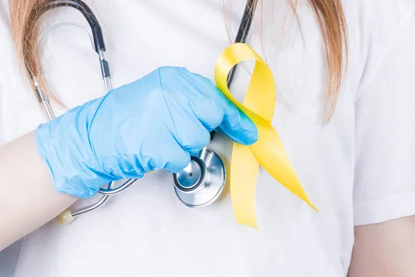 Young female in white t-shirt holding yellow ribbon awareness symbol for suicide, sarcoma bone cancer, bladder cancer, liver cancer and childhood cancer concept. Health care.