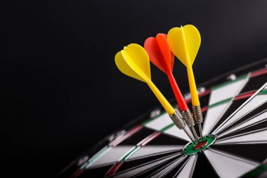 Dart tahtasının ortasına kırmızı ve sarı oklar. İş hedefi kavramı, başarı ve kazanç.
