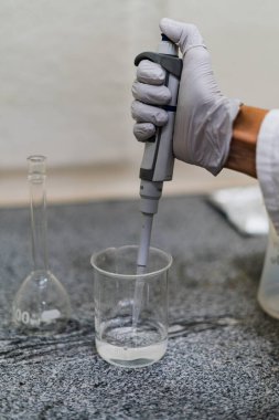 Gri eldivenli el laboratuarda kimyasal analiz yapıyor.