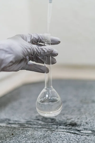 hand with gray glove doing chemical analysis in the laboratory