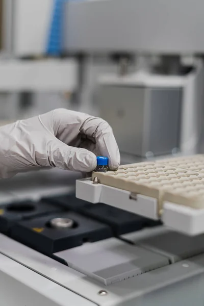 Gri eldivenli el laboratuvar ekipmanları üzerinde analiz yapıyor.