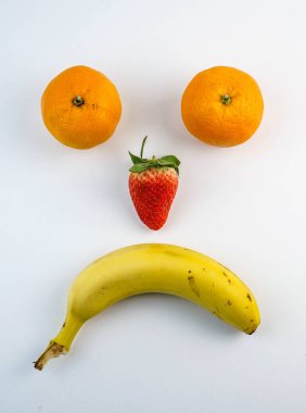 Muz, çilek ve portakaldan yapılmış mutlu ve üzgün yüzler.