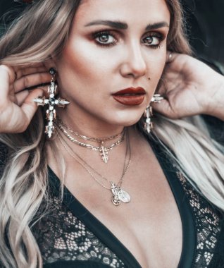 Gül, makyaj ve haç küpeli dini bir model.