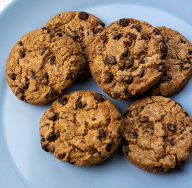 Mavi tabak çikolatalı kurabiye ve bir bardak süt.