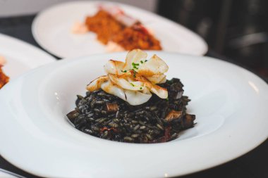 Lüks bir restoranda nefis bir deniz ürünleri yemeği Paella stili mürekkep balığı mürekkebi siyah pirinç.