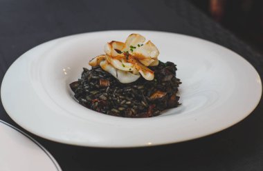 Lüks bir restoranda nefis bir deniz ürünleri yemeği Paella stili mürekkep balığı mürekkebi siyah pirinç.