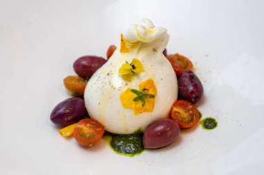 Peynirli mozarella salatası. Eşek sütü, kiraz rengi domates ve fesleğen. Hepsi bir gurme restoranından alınmış beyaz bir tabakta.