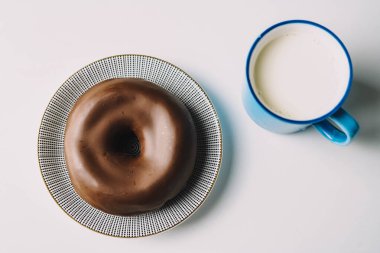 Beyaz arka planda lezzetli taze çikolatalı çörek. Lezzetli jöleli donut, bir fincan taze sütle yenmeye hazır.