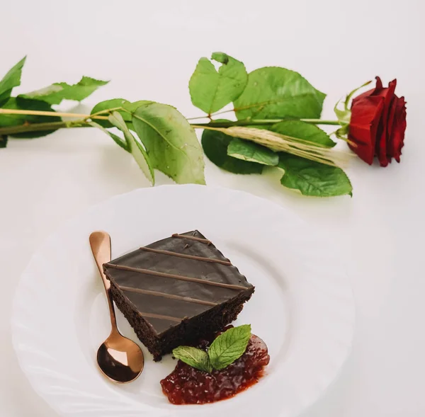 Uma Porção Bolo Chocolate Com Geléia Morango Uma Rosa Mesa — Fotografia de Stock