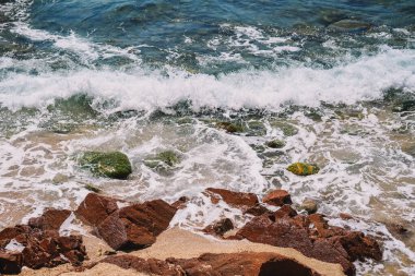 Akdeniz sahillerinde kayalar ve kumlar olan bir sahil resmi